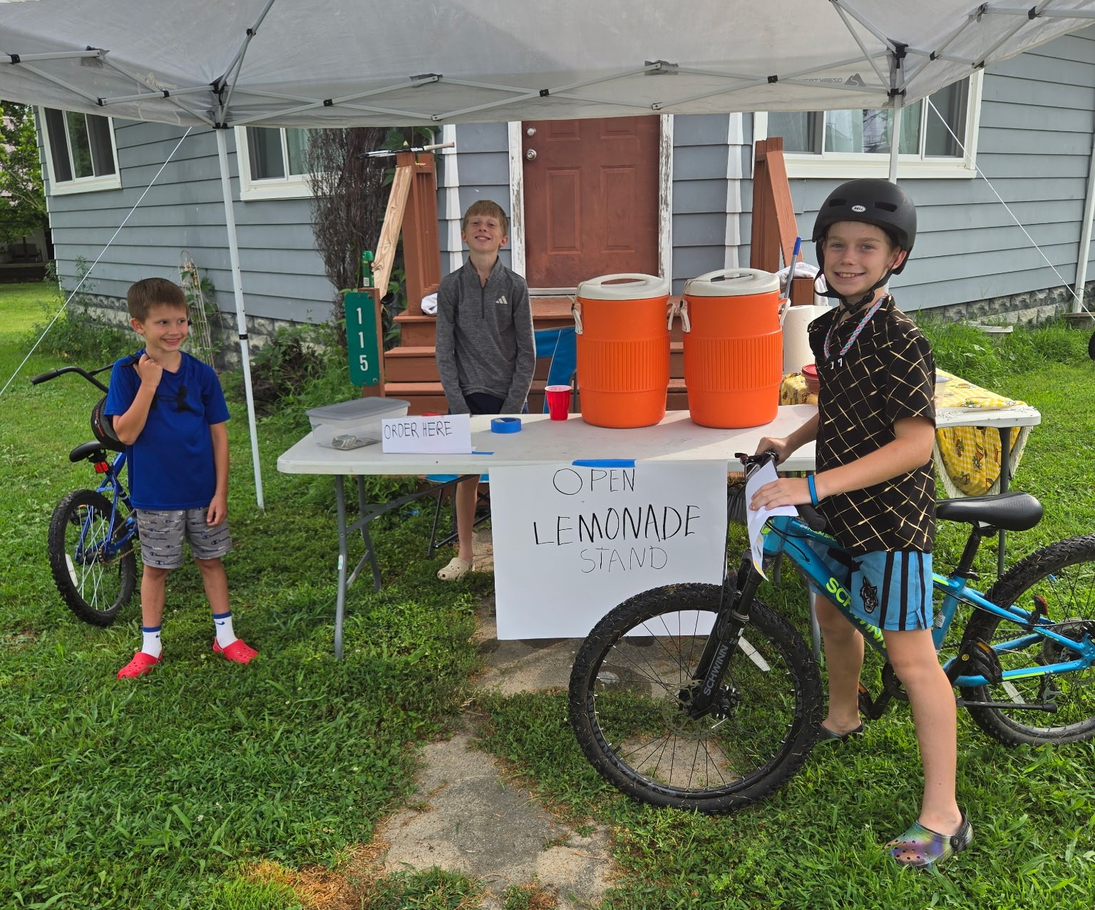 three boys working at a summer lemonade stand