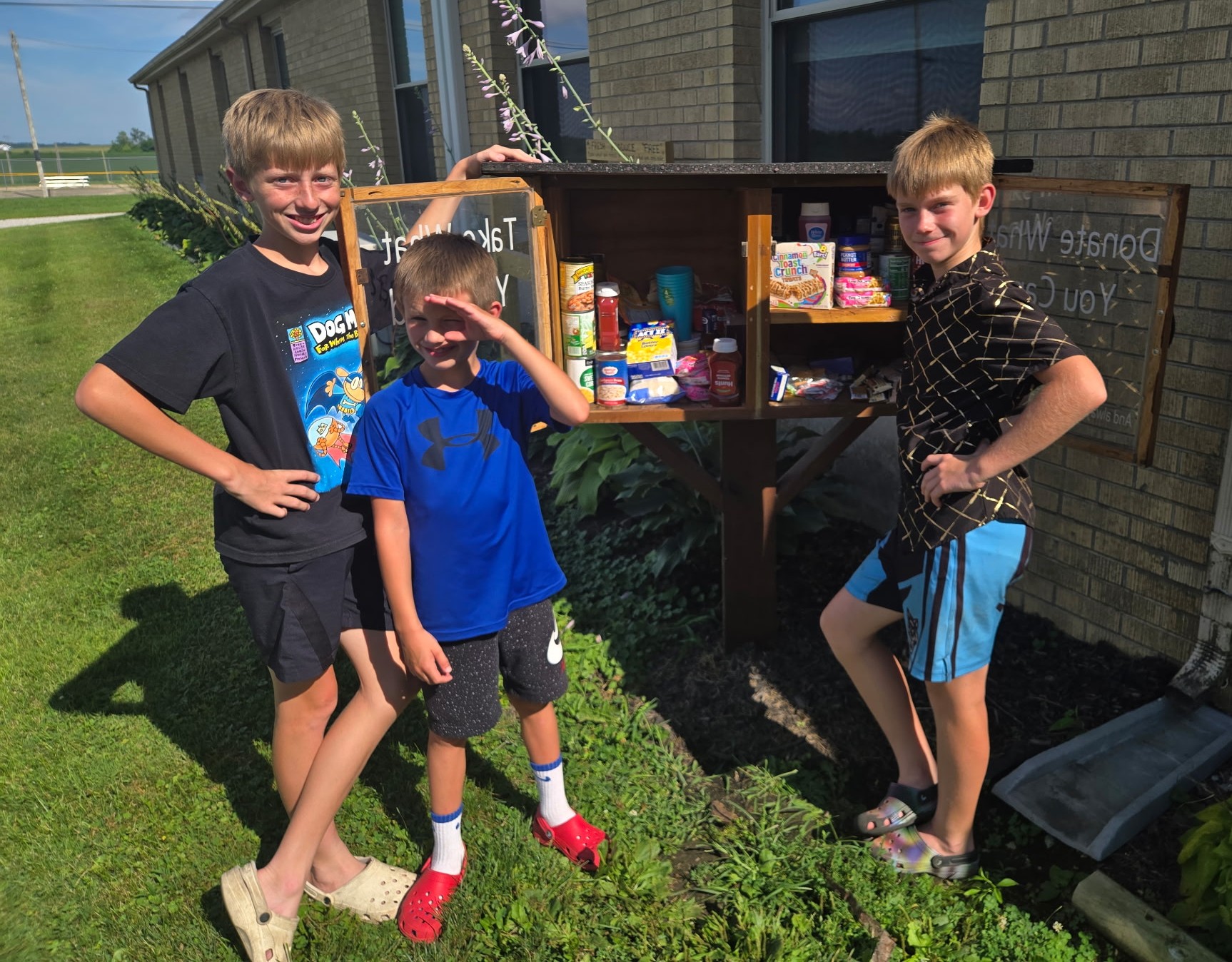 three boys adding food items to the blessing box