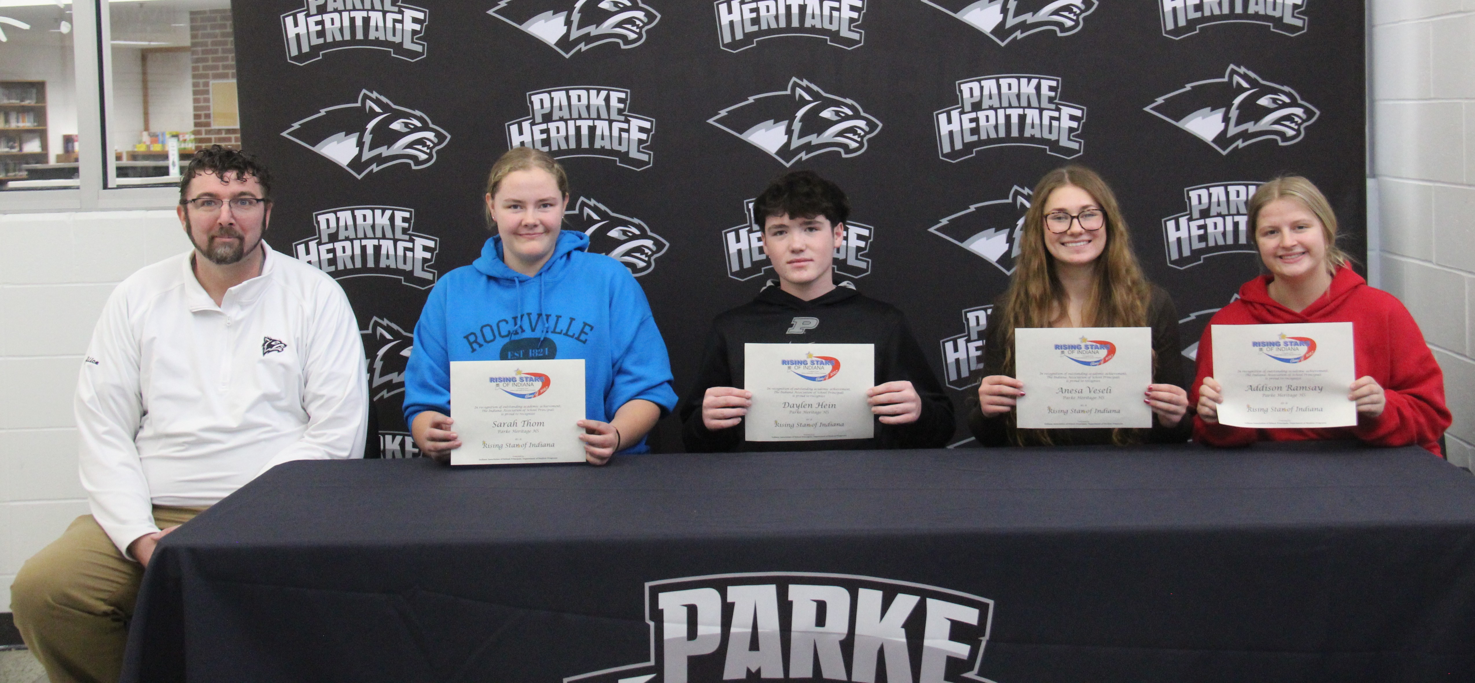 five people sitting at a table with four of them holding certificates