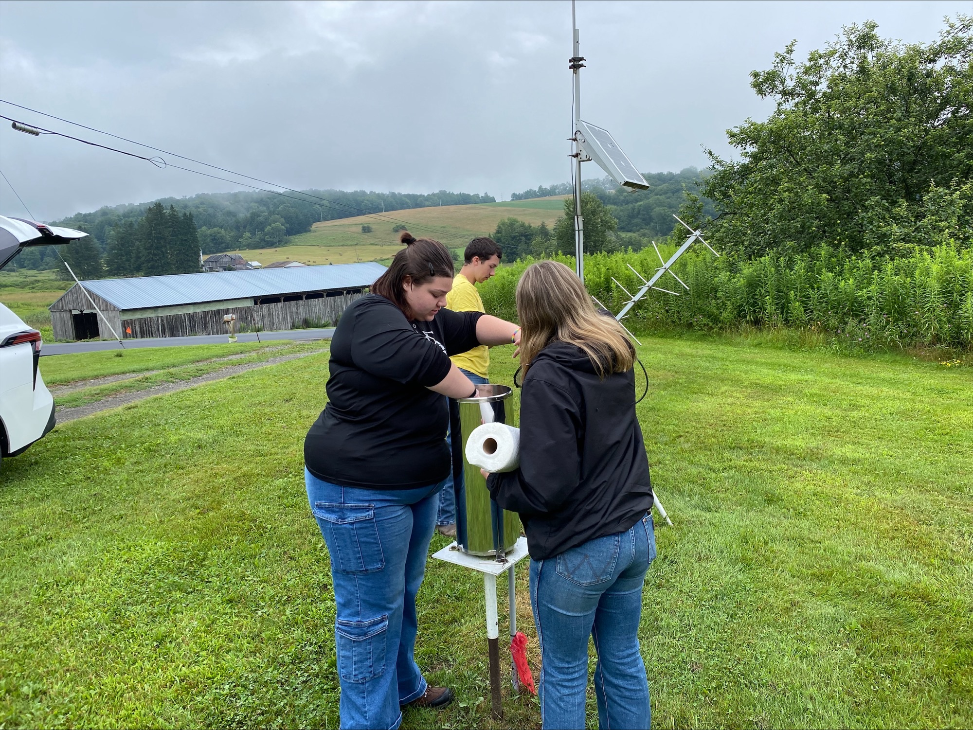 Two women collaboratively adjusting a radio antenna, showcasing teamwork and technical skill in a communication setup.
