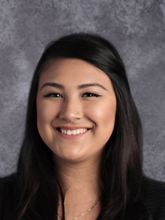 A smiling young woman wearing a black shirt and black jacket, exuding confidence and warmth.
