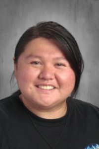 A woman wearing a black shirt smiles warmly at the camera, exuding confidence and joy.