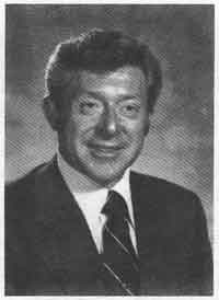 A black and white photograph of a man dressed in a formal suit, exuding professionalism and elegance.