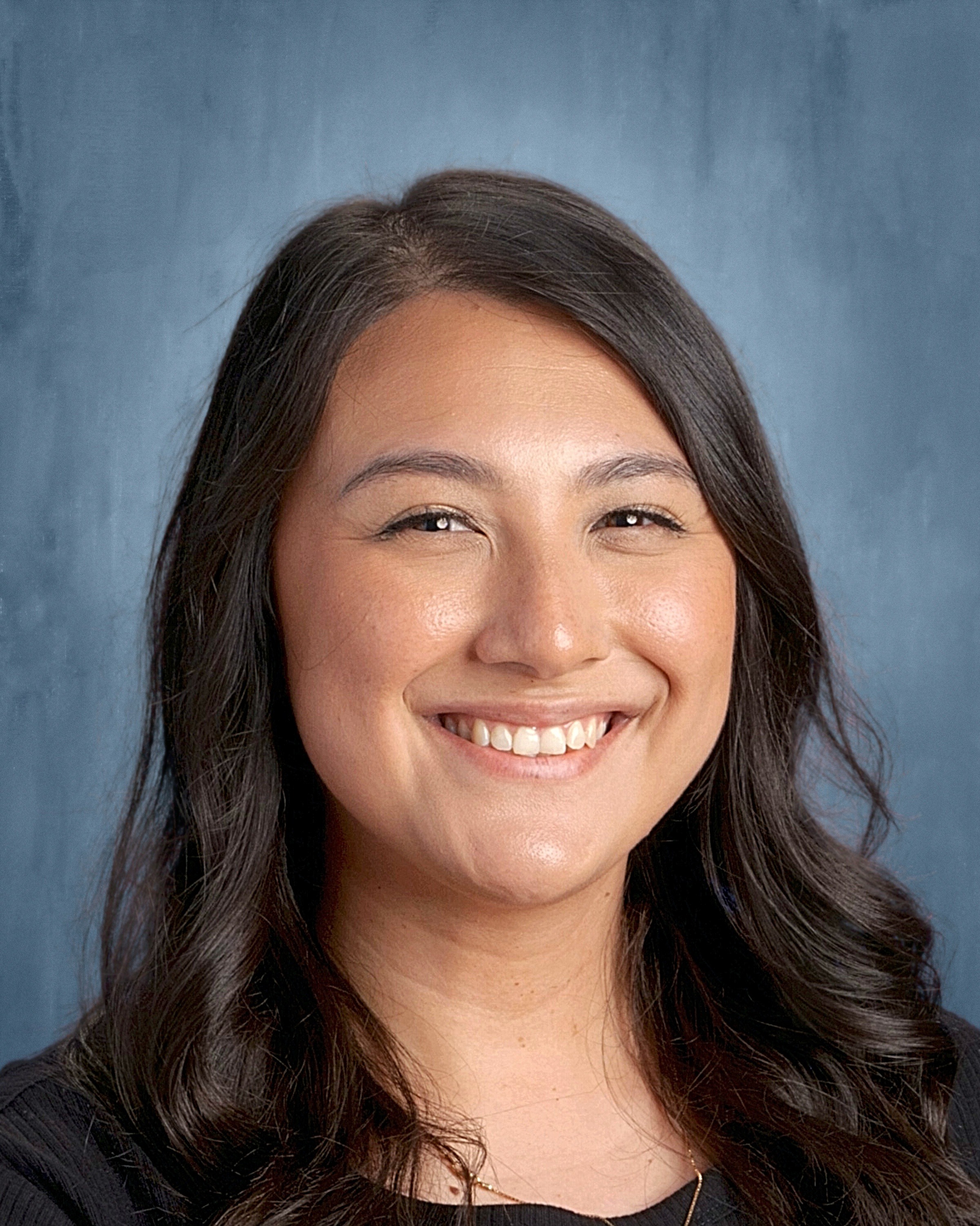 A smiling young woman wearing a black shirt and black jacket, exuding confidence and warmth.