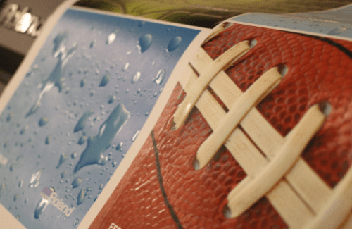 A close-up image showing a textured football with white laces next to a blue background featuring water droplets.