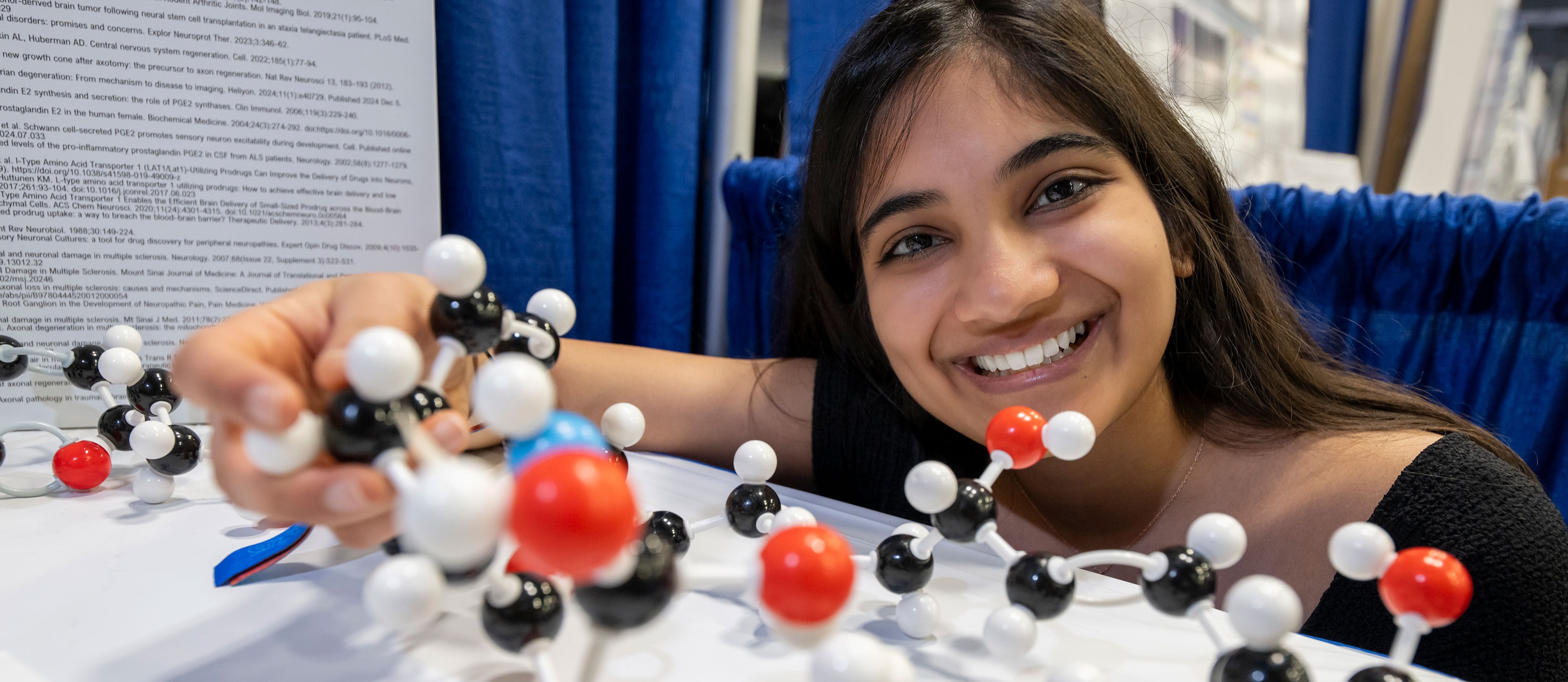 student smiling in front of science exhibit