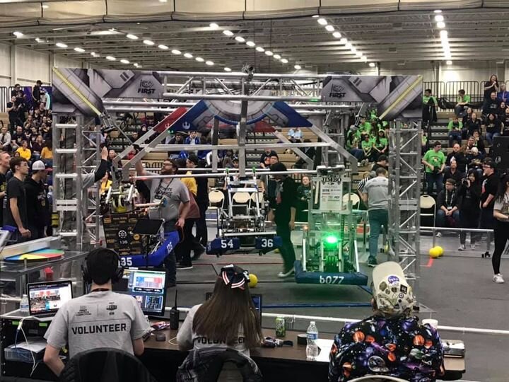 A large crowd gathers to watch an exciting robot competition, showcasing innovative technology and engineering skills.