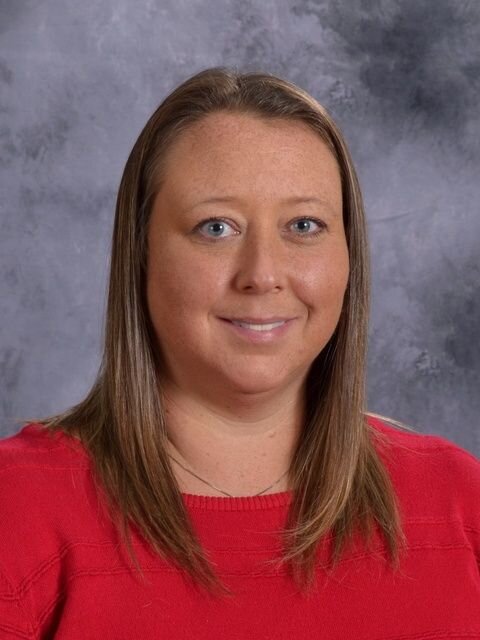 A woman wearing a red sweater poses confidently for a photograph, showcasing her vibrant style and personality.