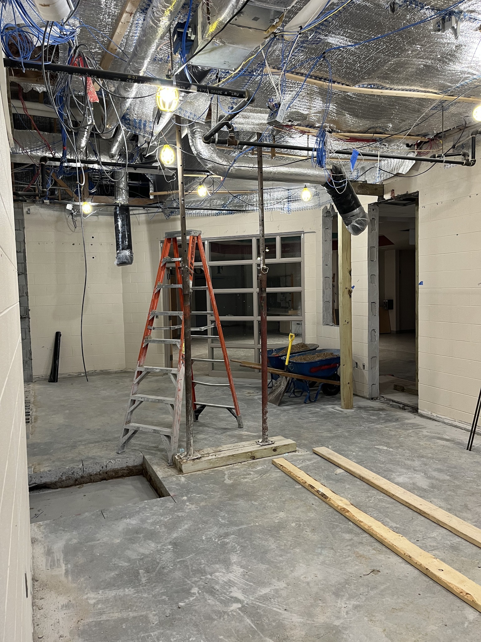 An unfinished interior space under construction, featuring a ladder, exposed wiring, and a partially completed floor.
