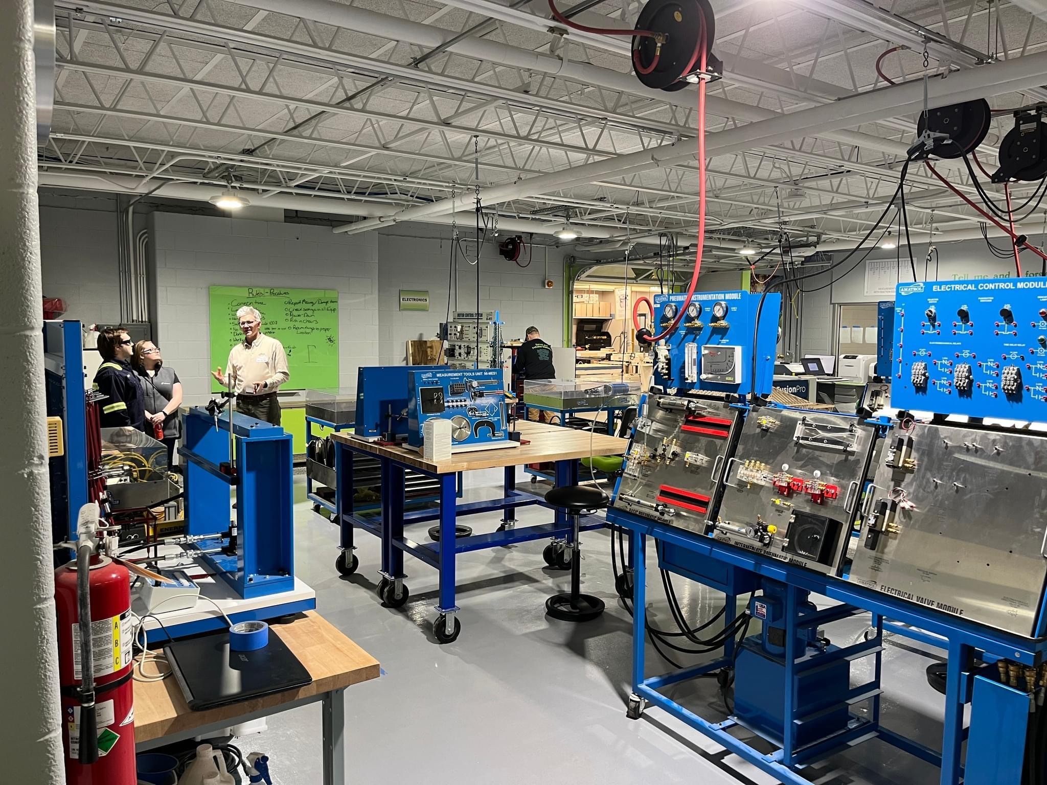 A workshop filled with blue machinery and equipment, where individuals are engaged in hands-on activities, showcasing a collaborative learning environment.