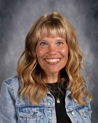 A woman with long hair is wearing a stylish denim jacket, exuding a casual and confident vibe.