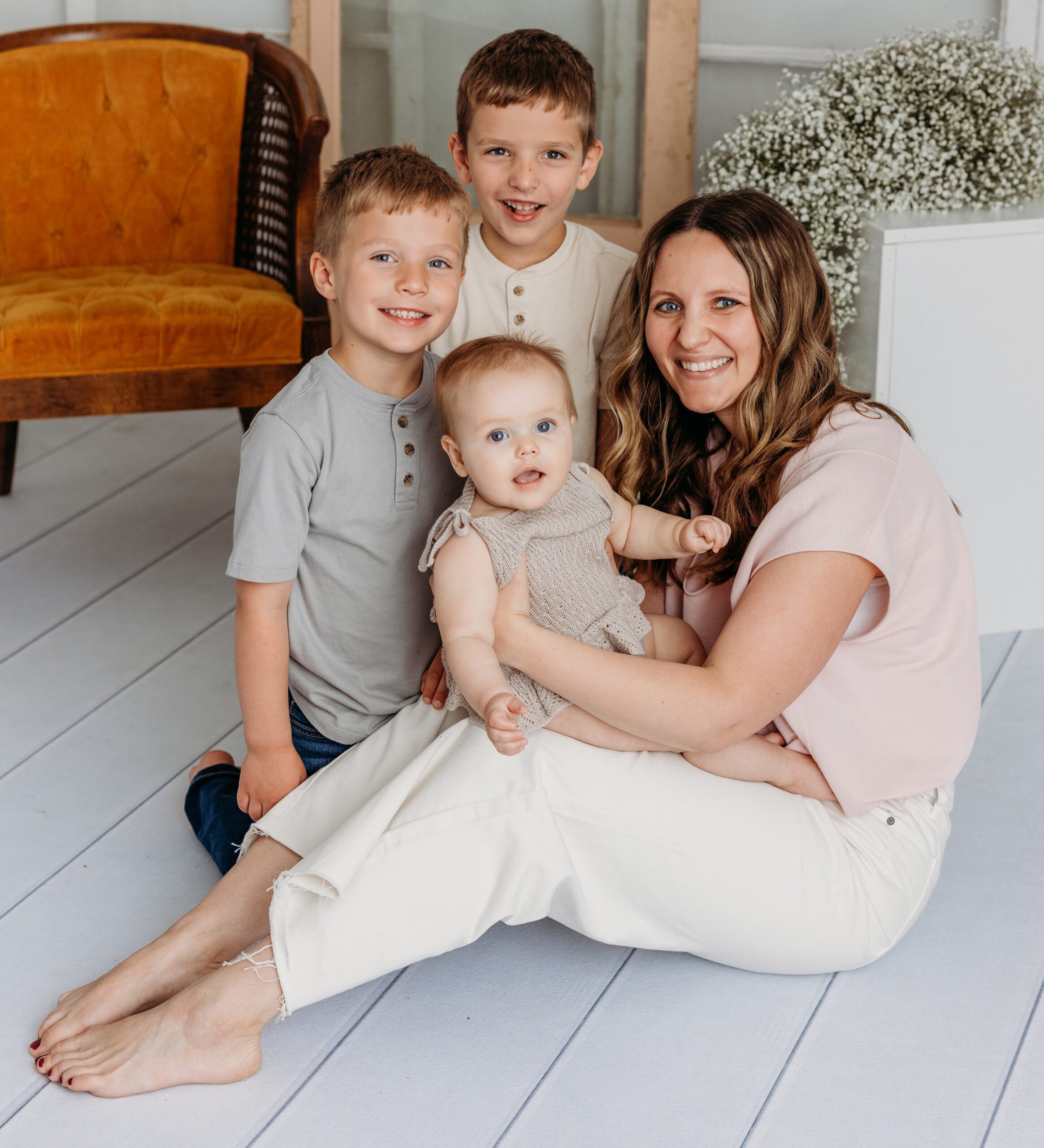A woman and two children sit on the floor, surrounded by warmth, in front of a cheerful yellow chair.