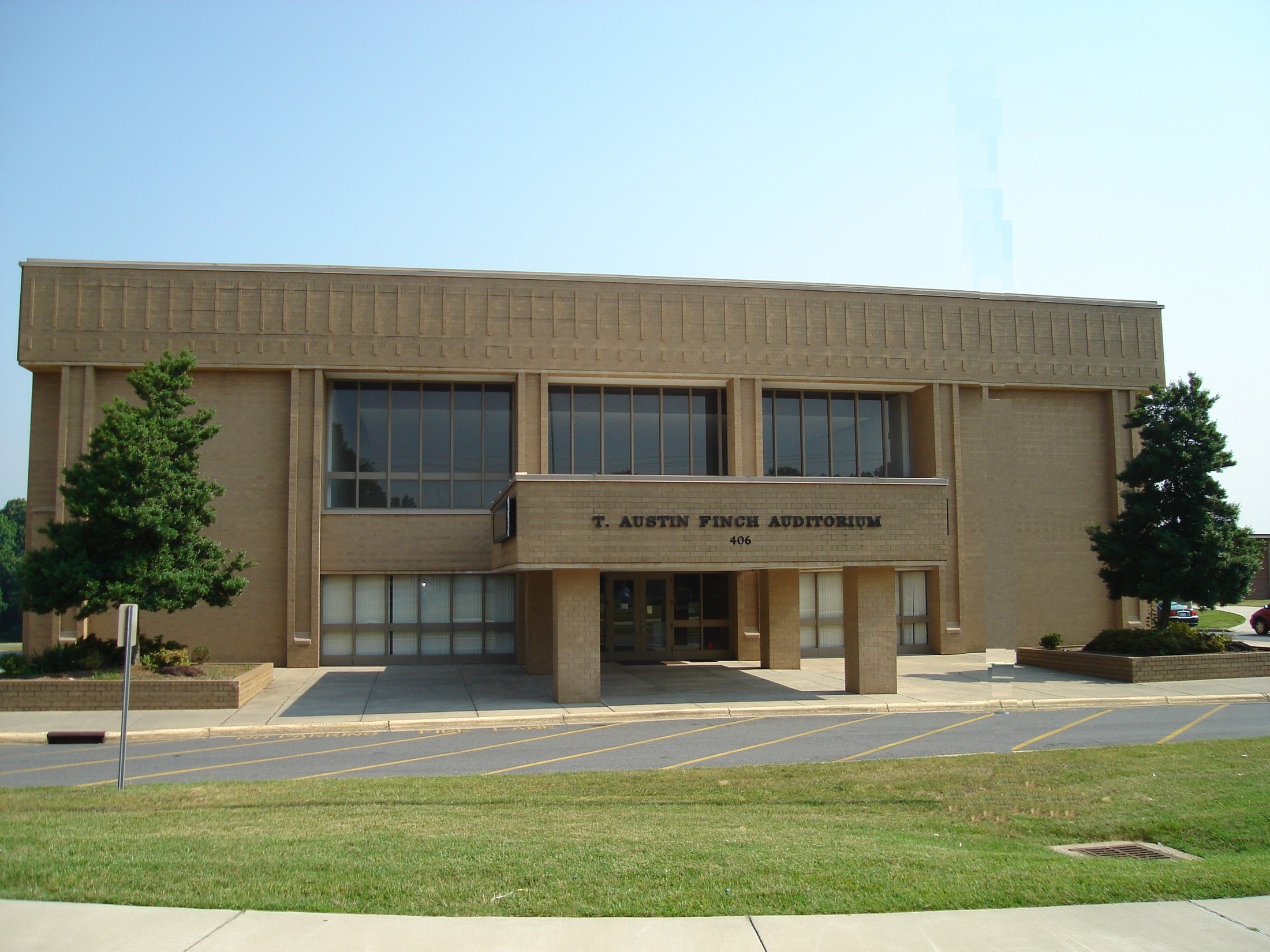  A tan building stands prominently against a clear sky, showcasing its neutral color and architectural design.