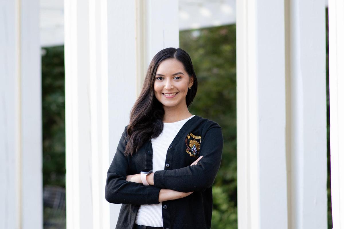 A woman wearing a black jacket over a white shirt poses confidently for a photograph.