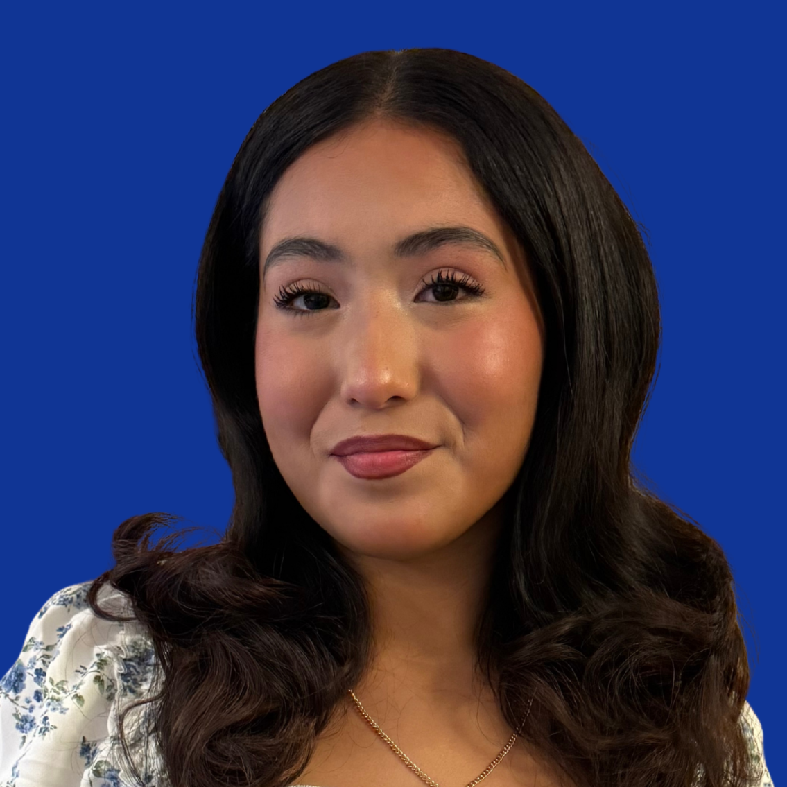 A woman in a blue floral dress holds a certificate, reading "Student of the Month" in front of a blue background.