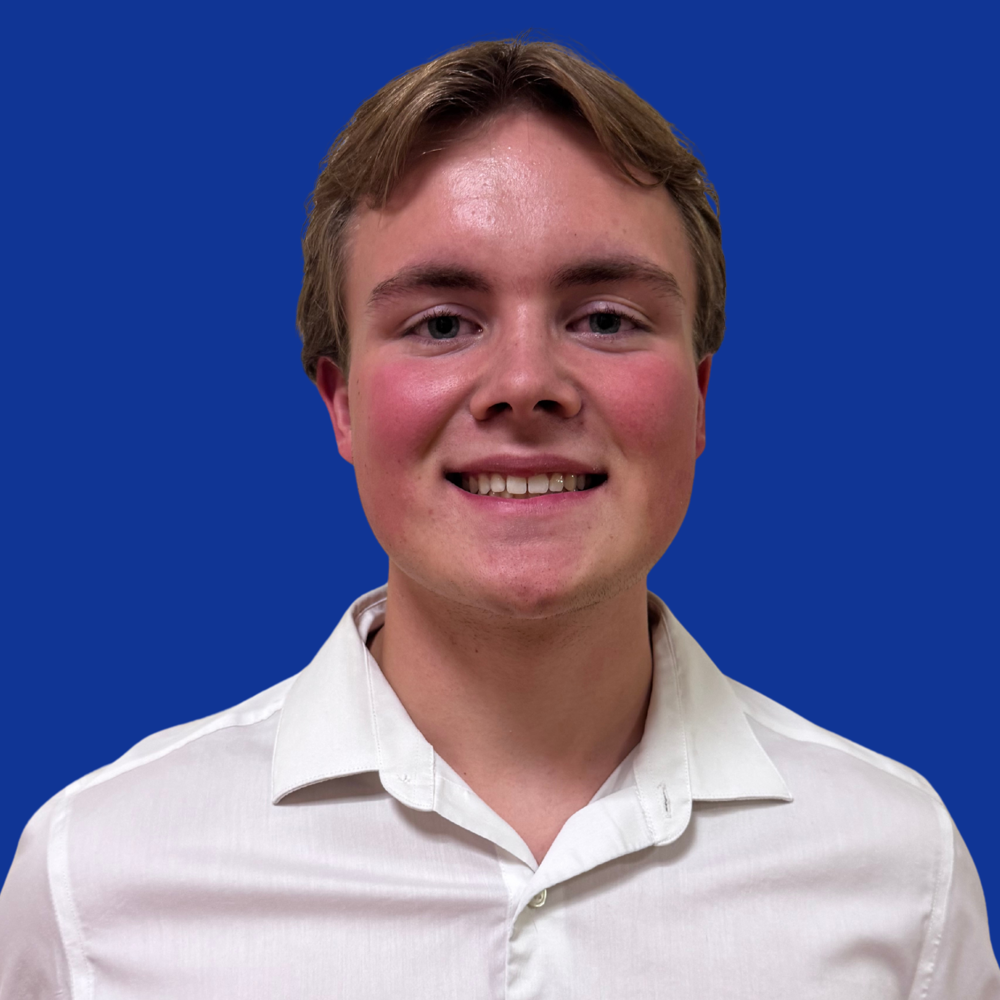 A man wearing a white shirt poses with a smile against a solid blue background.