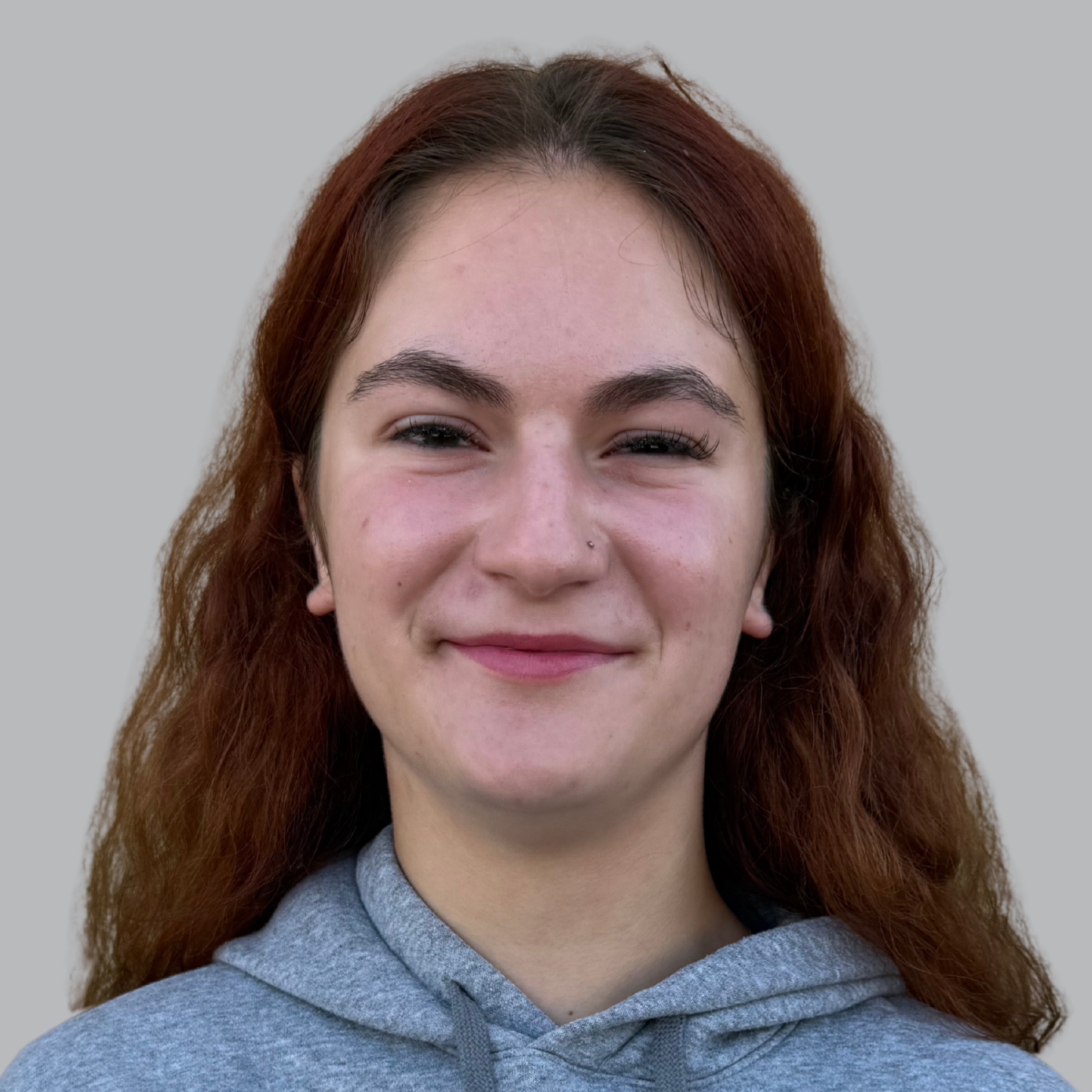 A young person smiles, wearing a gray hoodie with "WOLVES" printed in black on the front.