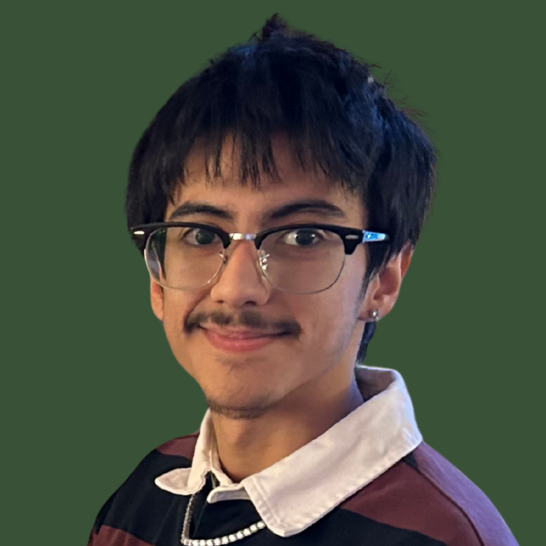 A man with short black hair wearing glasses and a striped shirt with a necklace. He is standing against a green background.