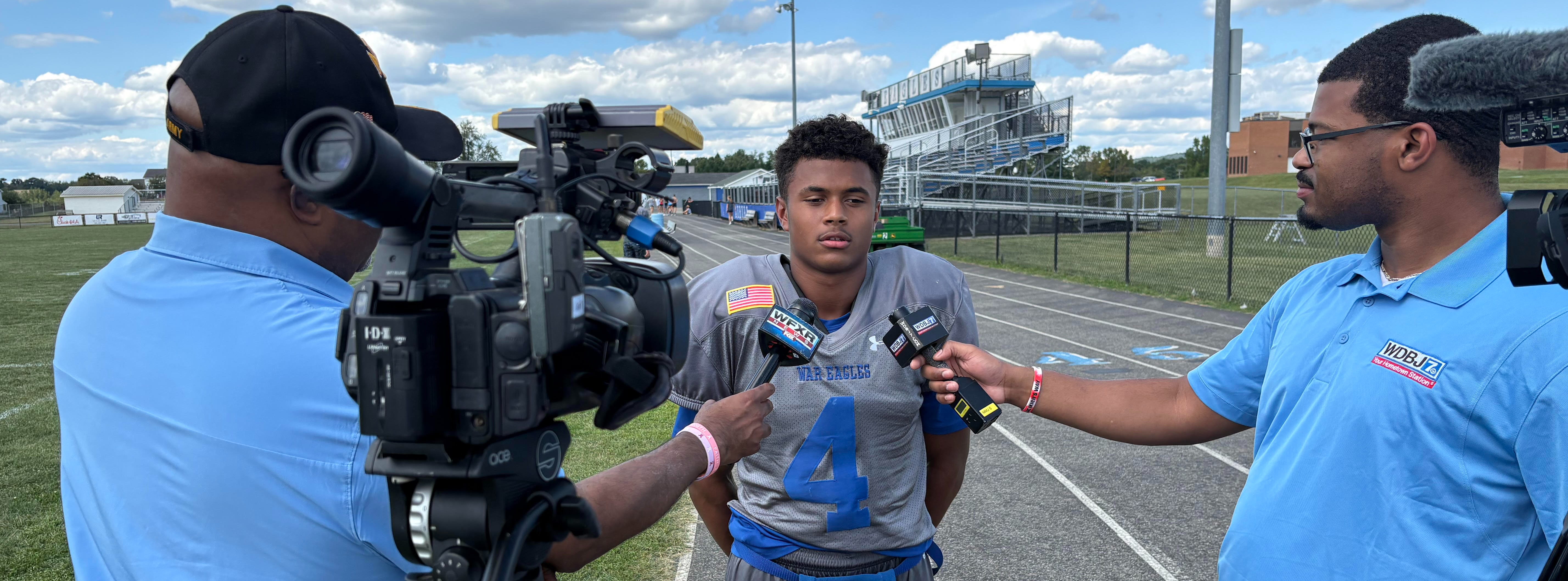AHS football player being interviewed by two news stations
