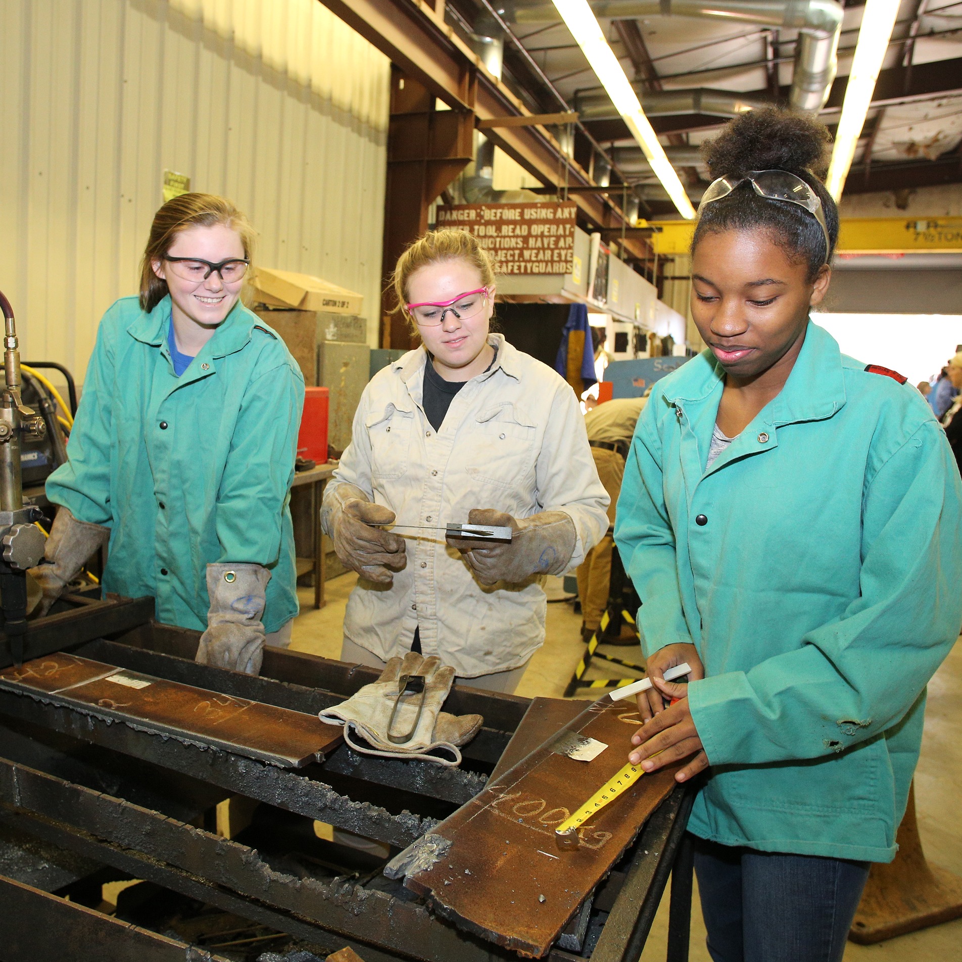 3 students measuring metal with tape measure