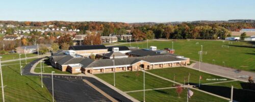 Aerial view of a school building surrounded by a parking lot, showcasing the layout and surrounding area.