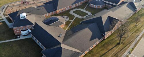 Aerial view of a school building showcasing its roof and surrounding landscape, emphasizing its architectural design.
