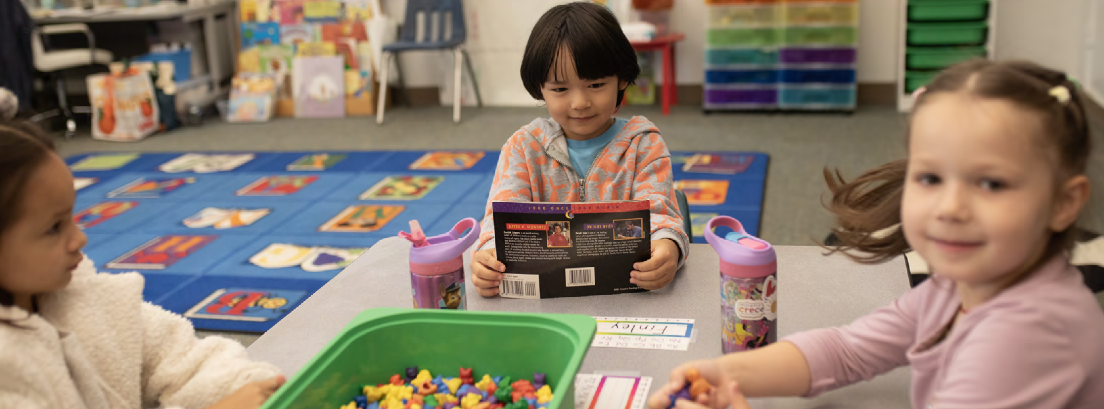 Children participating in a classroom learning activity at a table.