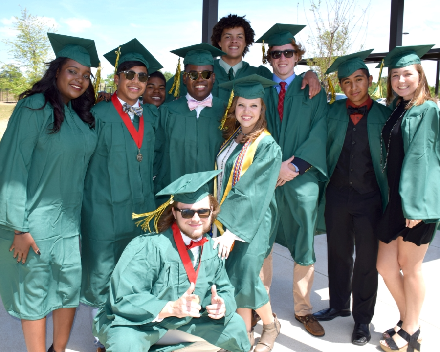 A group of graduates smiles together for a celebratory photo, showcasing their caps and gowns.