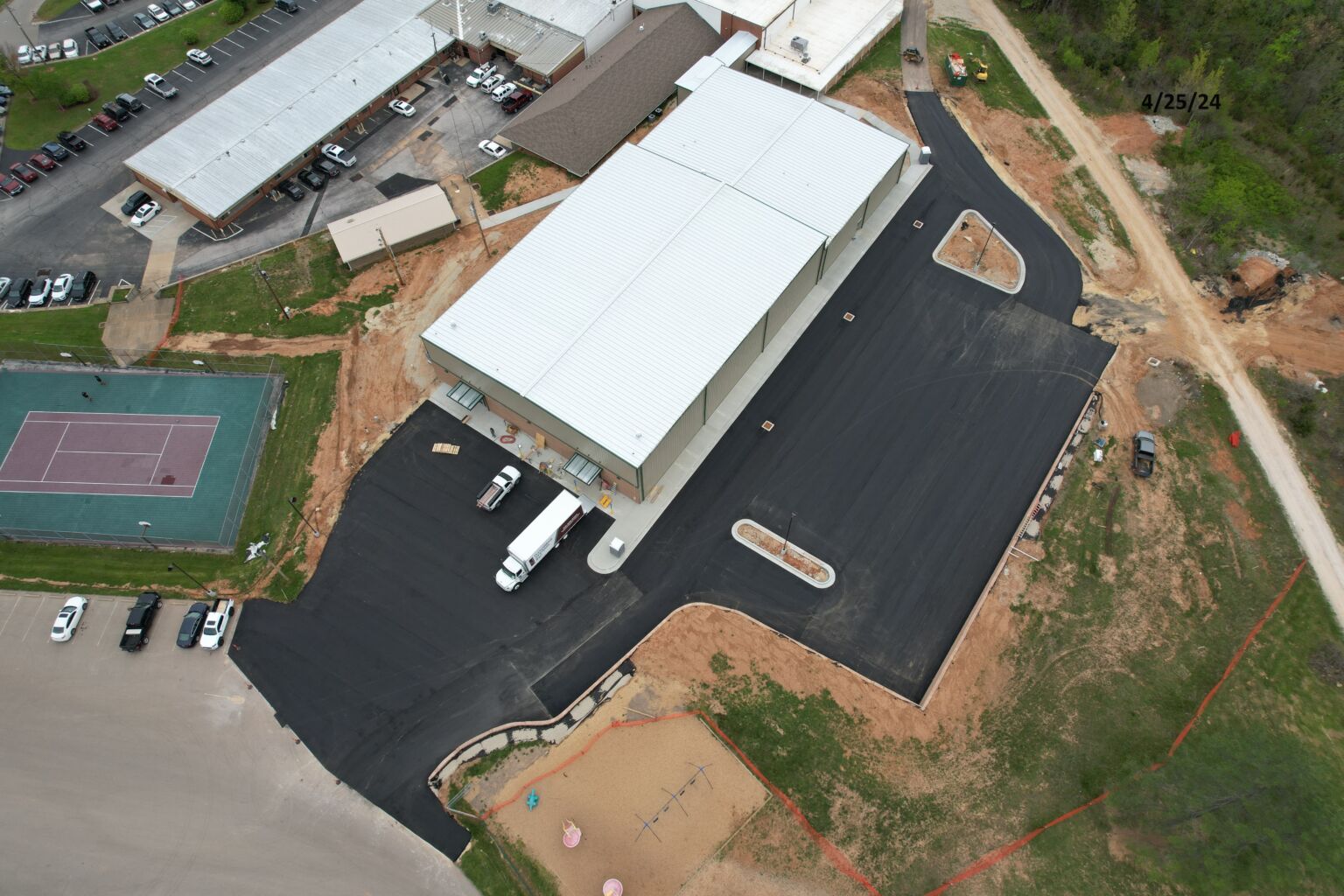 Aerial view of a large building featuring a tennis court, showcasing the structure and recreational area from above.