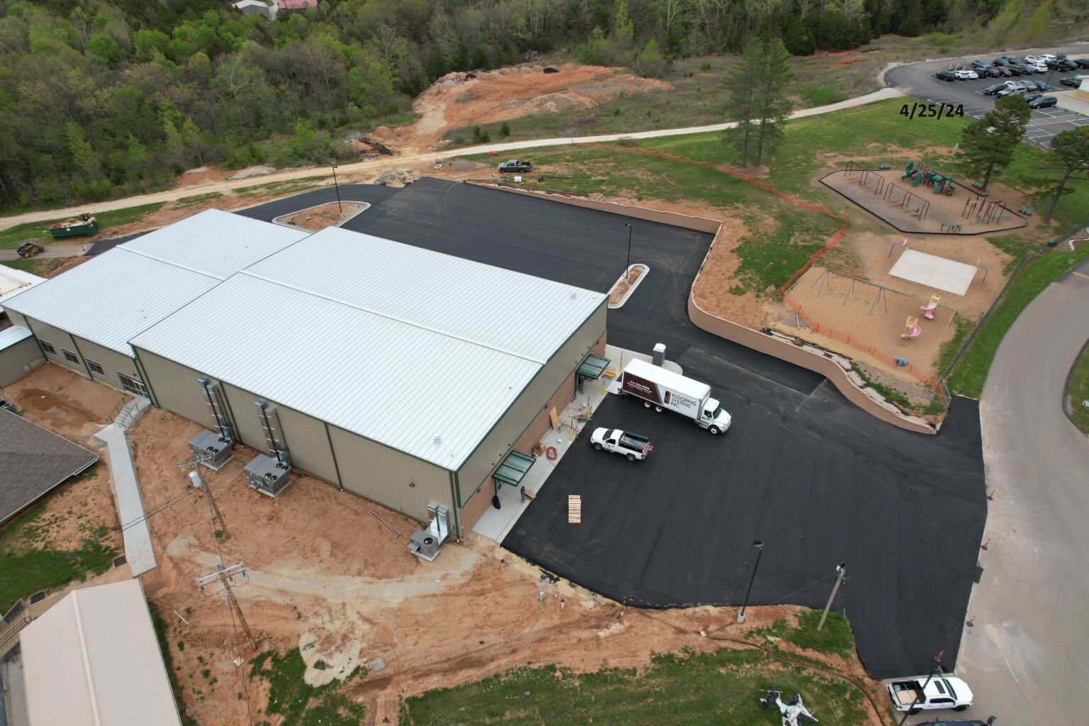 Aerial view of a large building with a truck parked in front, showcasing the structure and surrounding area from above.