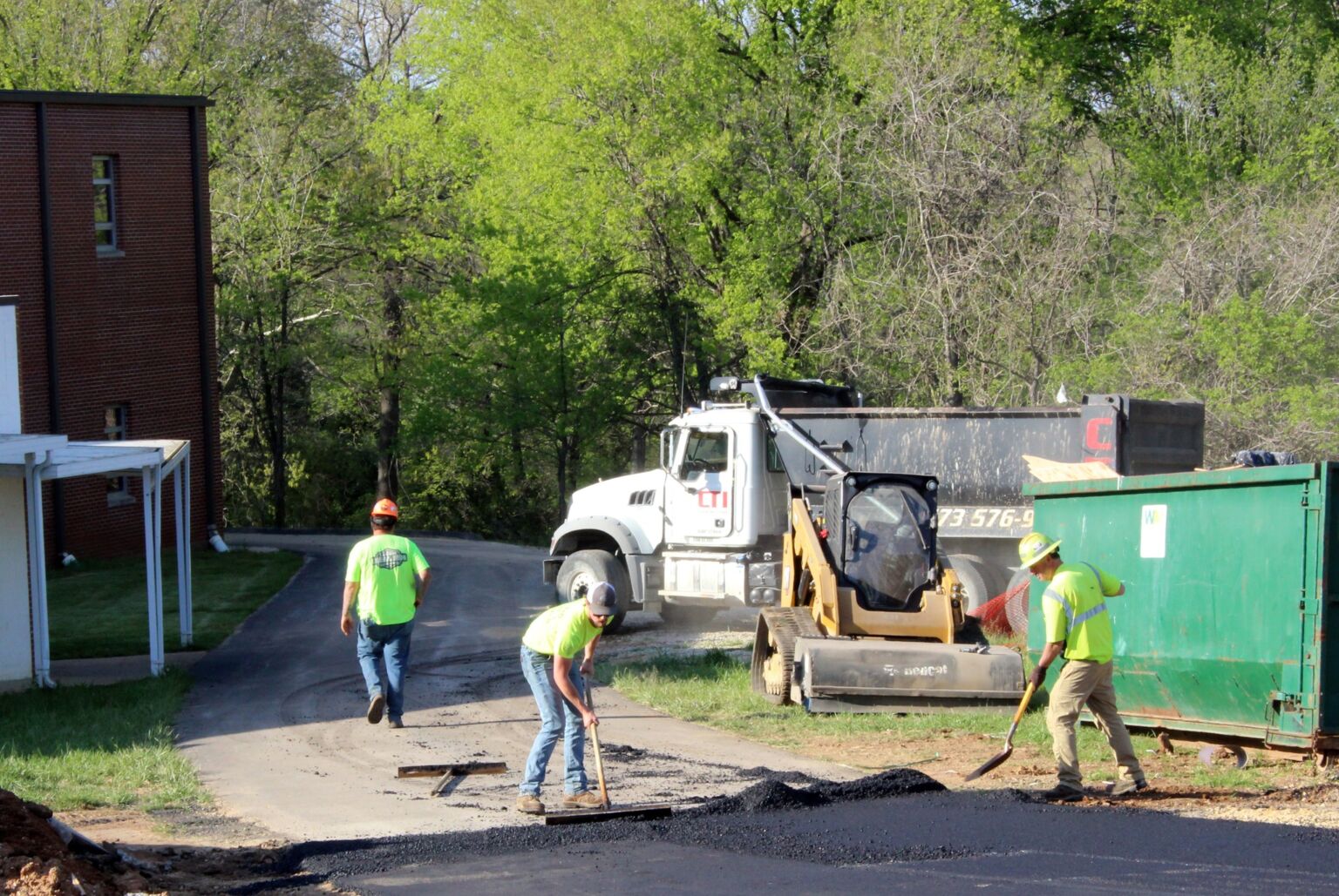 A group of men collaborating on road construction, using tools and machinery to improve the roadway.