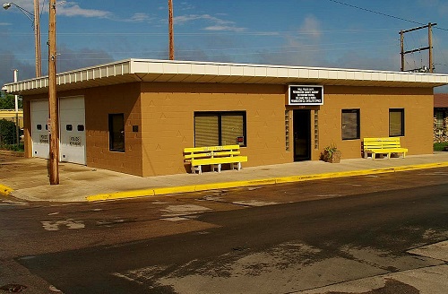A small tan building with a bench positioned in front, inviting for rest and relaxation in a serene setting.