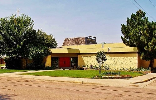 A yellow building featuring a prominent red door and a matching red doorbell, creating a vibrant contrast.