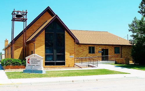 A church featuring a prominent steeple and a sign displaying the word "church" in front of it.