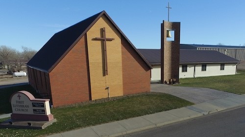 A church featuring a prominent cross on its facade, accompanied by a sign that reads "church."