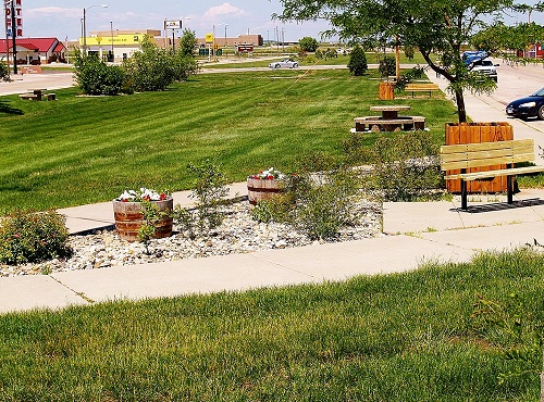 A bench positioned in a grassy area adjacent to a road, inviting passersby to take a moment of rest.