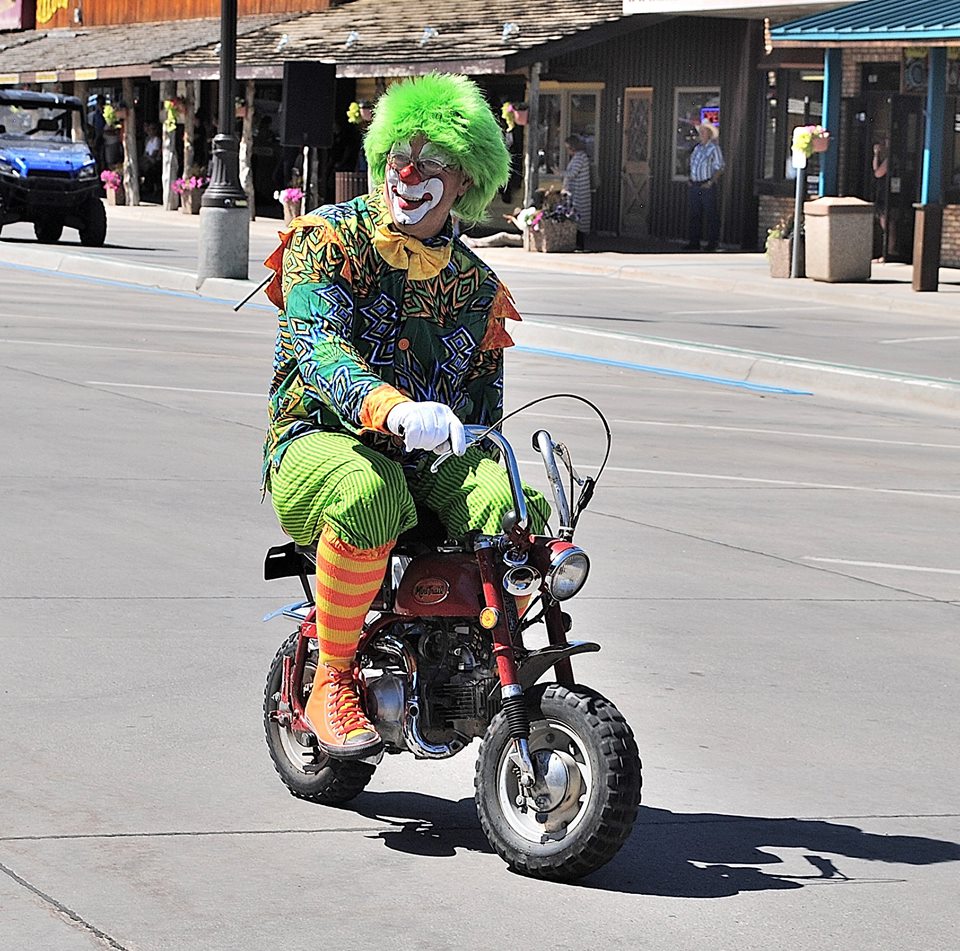 A clown in colorful attire rides a motorcycle, showcasing a playful and whimsical scene on the road.