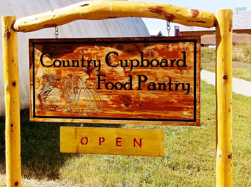 A rustic country cupboard filled with various food items, showcasing a well-organized pantry with jars and canned goods.