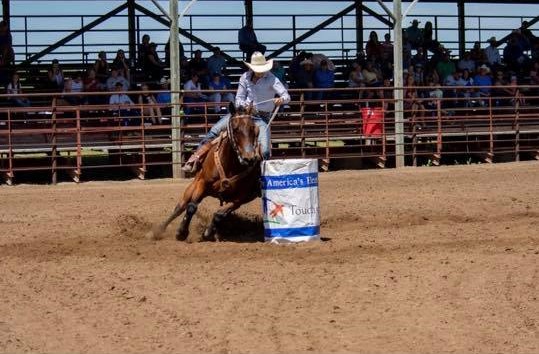 A rider on horseback navigates around a barrel in an arena, demonstrating expertise in equestrian skills.