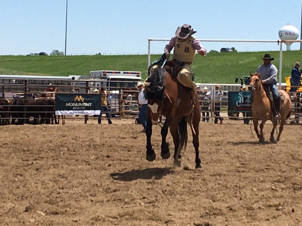 A cowboy skillfully rides a horse in a vibrant rodeo arena, showcasing the excitement of the event.