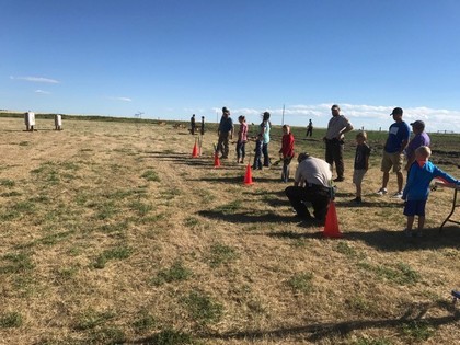 A group of people gathered around traffic cones in an open field, engaged in discussion or activity.
