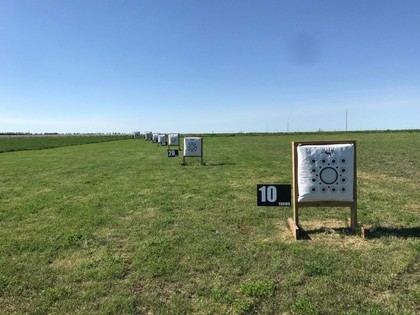 A vast field featuring a target prominently positioned in its center, surrounded by open grassland.