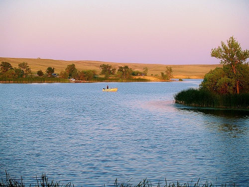 A serene evening scene featuring a boat gently floating on a tranquil lake, surrounded by soft twilight hues.