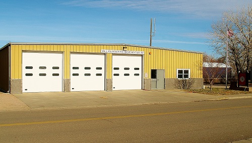 A yellow building featuring two garage doors and a flag pole prominently displayed in front.