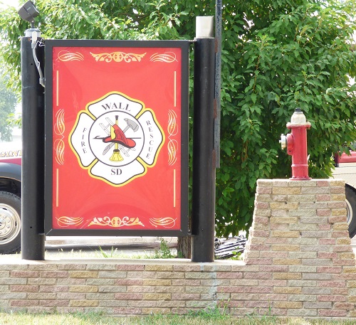 A fire department sign mounted on a textured brick wall, indicating the location of emergency services.