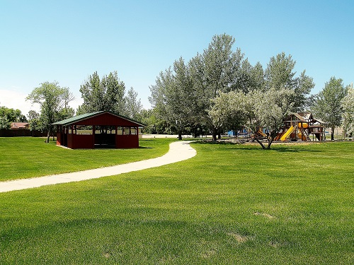 A vibrant park featuring a playground and a striking red building in the background, inviting families to enjoy outdoor activities.