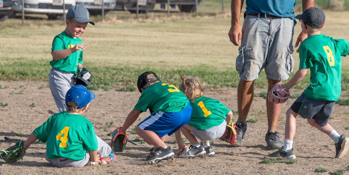 A group of children joyfully playing baseball on a sunny field, showcasing teamwork and enthusiasm for the game.
