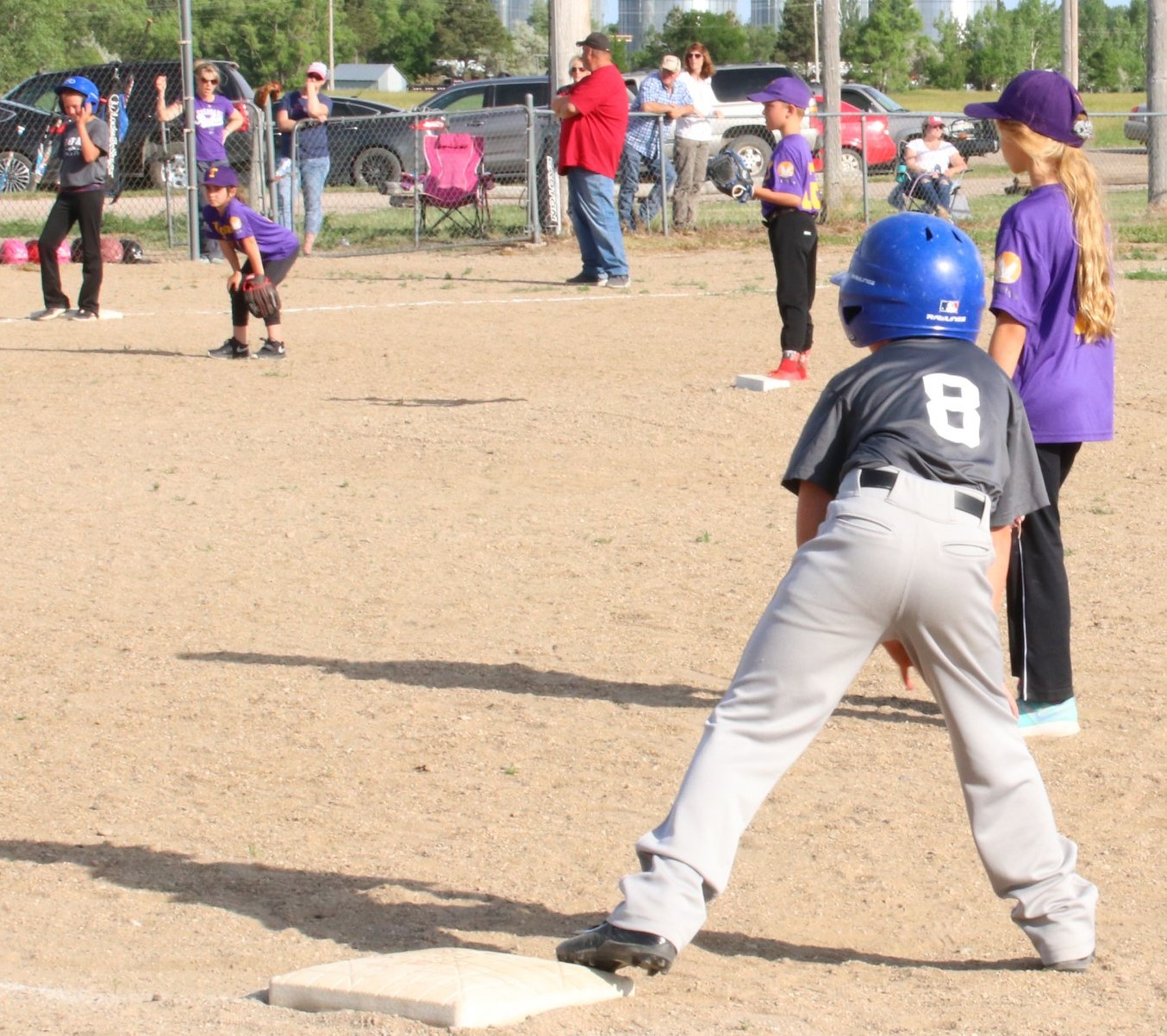 A young boy joyfully playing baseball, swinging a bat in a sunny outdoor setting.