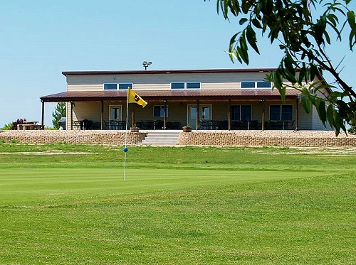 A scenic golf course featuring a house in the background and a flag positioned on the green.