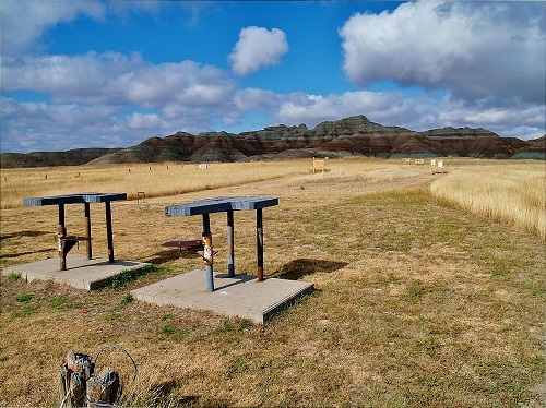 Two benches positioned in a serene field, with a majestic mountain rising in the background.